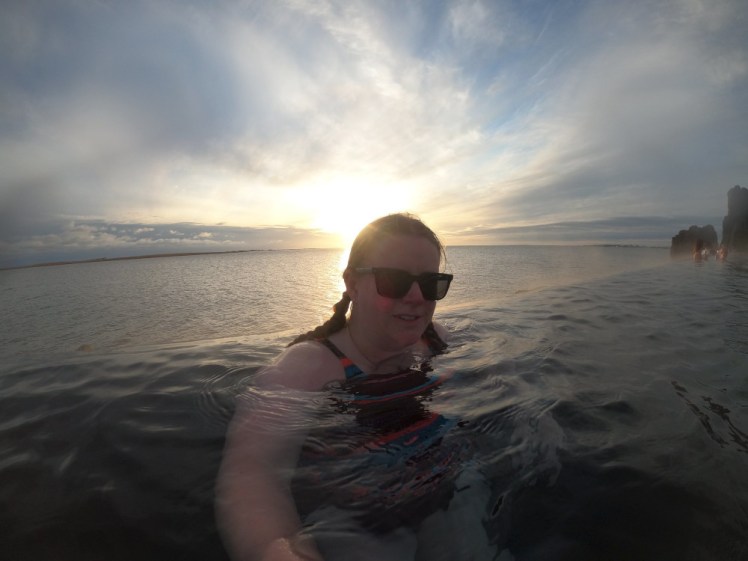 A selfie by the edge of the infinity pool with the low sun behind me. I'm in the Sky Lagoon; behind me is the fjord and there's no real distinction between the two.