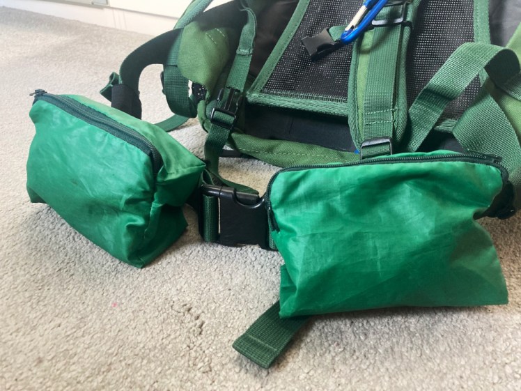 Two boxy rectangular pouches of green nylon attached to the hip belt of my bag. They're both a bit wrinkly because they don't hold their own shape but they're quite voluminous which makes them useful.