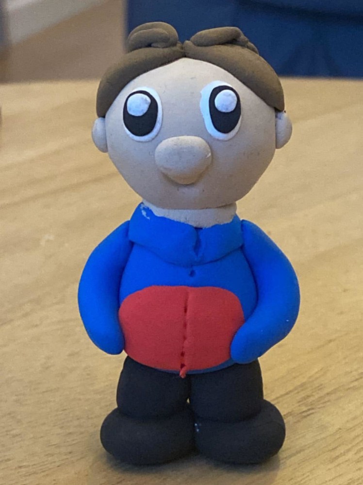 A Guide mini me, in blue and red uniform, with huge eyes and brown hair.