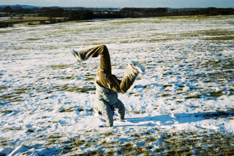 Pat doing handstands on the hill in the snow