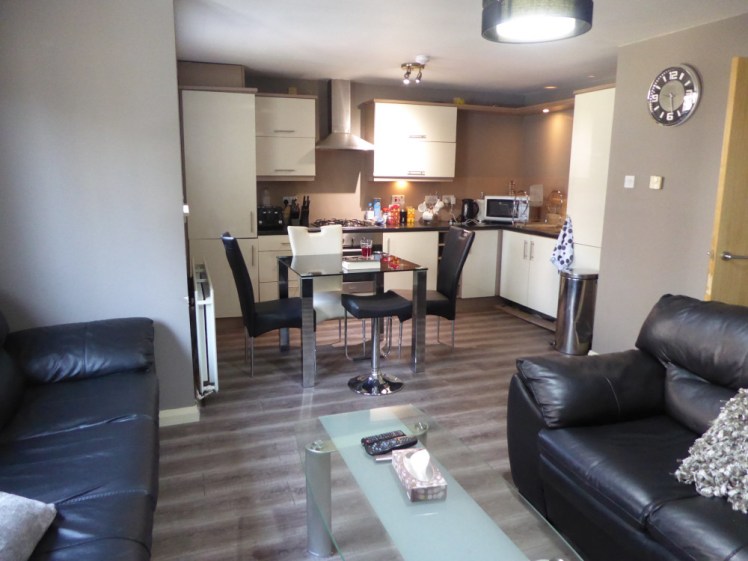 My apartment in Glasgow. This room is the open-plan kitchen-living room, with black leather sofas, a glass kitchen table with four chairs around it and a proper kitchen.