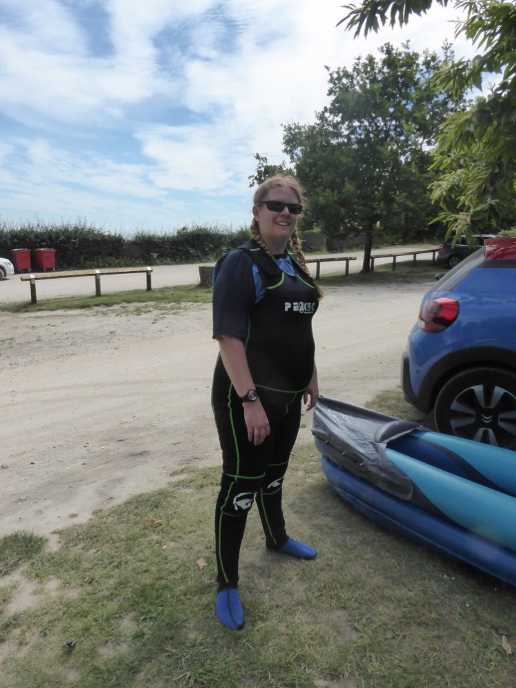 Me in my full-length wetsuit in a sandy car park. I'm wearing a blue rash vest underneath the wetsuit & blue neoprene socks.
