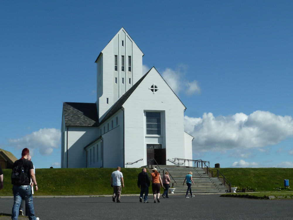 The church at Skalholt, a relatively large church by Icelandic standards, white, with clean lines and edges. It's raised slightly above the car park.