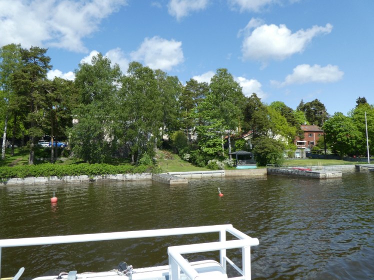 Sailing past an island covered in trees and grass where every house has its own jetty.
