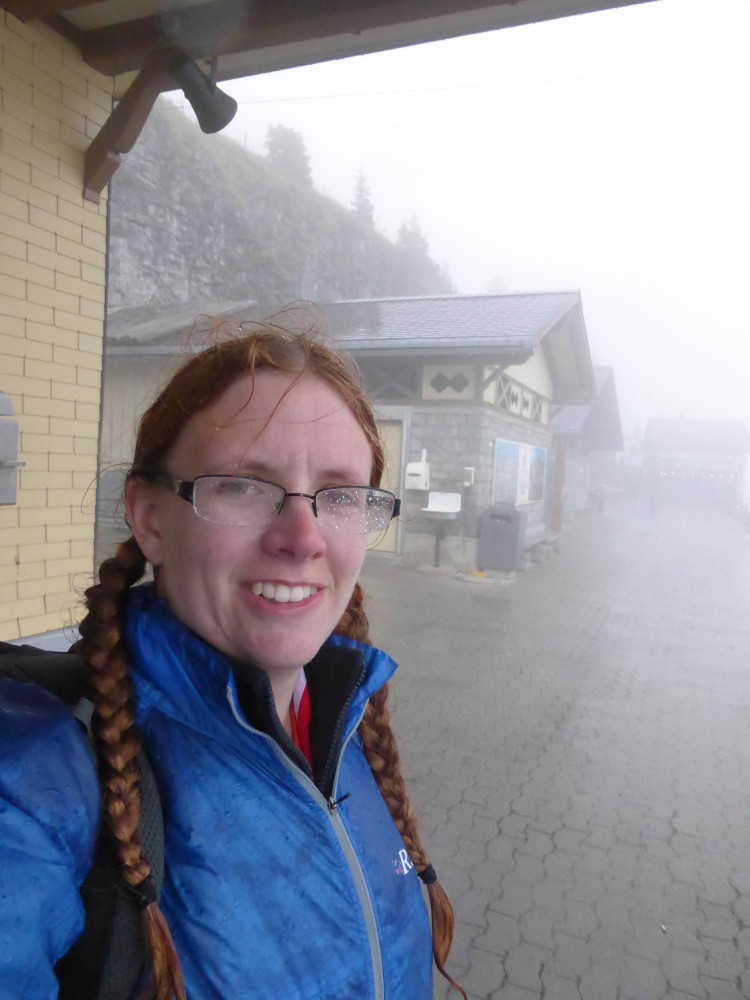 A selfie on the train platform. It's raining so heavily that it all looks like a thick mist. I'm wearing my blue windshirt over my orange t-shirt and I look very damp.