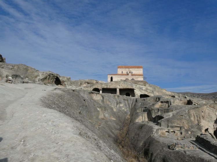 A brick-built church perched on top of the cave city, looking very out of place above the open galleries and steep sides.
