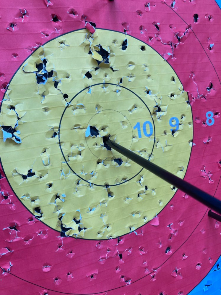 An arrow right in the centre of the gold in an archery target.