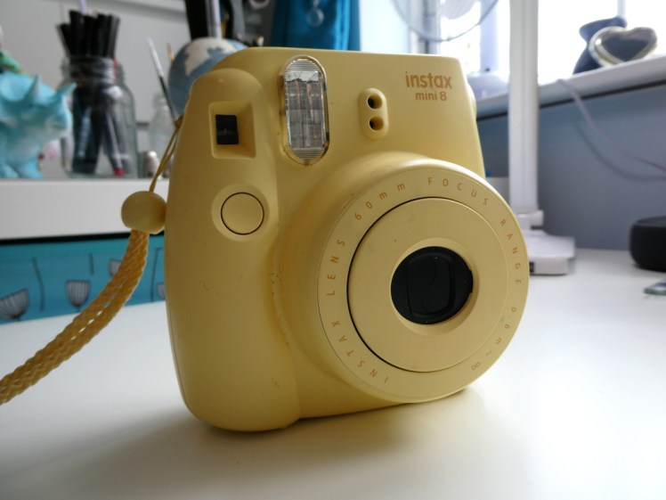 My Instax Mini 8 camera. It's a squarish but also bubble-shaped yellow instant camera.