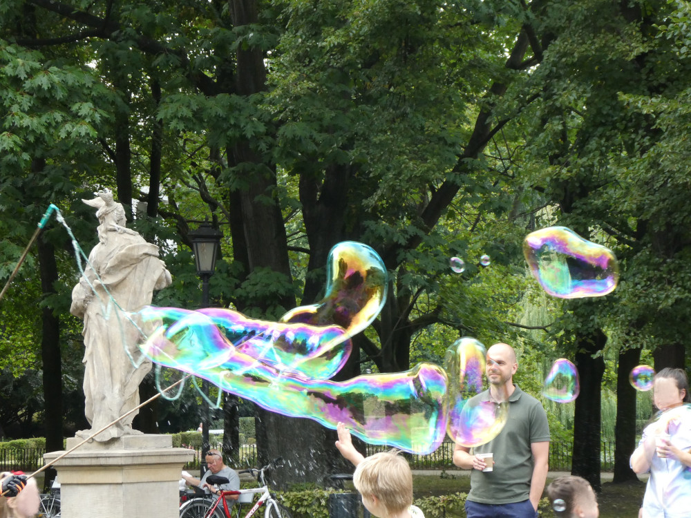 Giant bubbles being blown across the park, with great streaks of gold and pink and green and blue in them. There are a few children in the edges of the picture because it's impossible to get pictures of bubbles without them but I've smudged their faces away and turned them into the creepy faceless people from Doctor Who season two.
