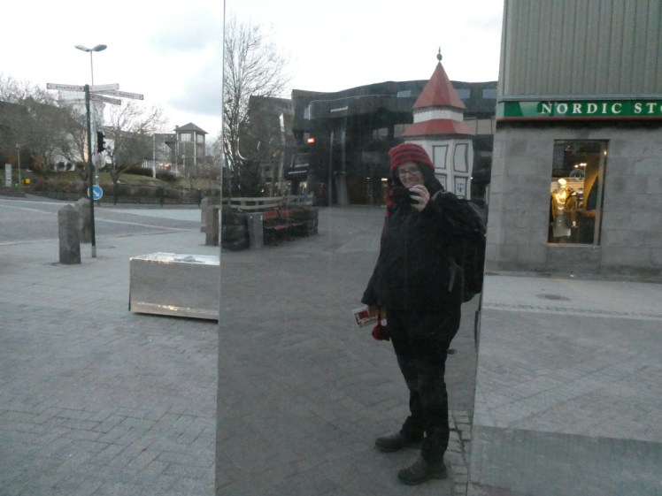 A selfie in a mirrored pillar in the middle of Lækjartorg with Te og Kaffee barely visible in the reflection behind me.
