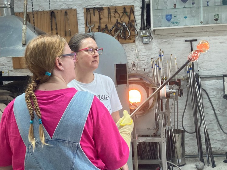 Me holding a lump of glass on the end of my pole. I'm holding it up and turning it so it settles onto its stem.