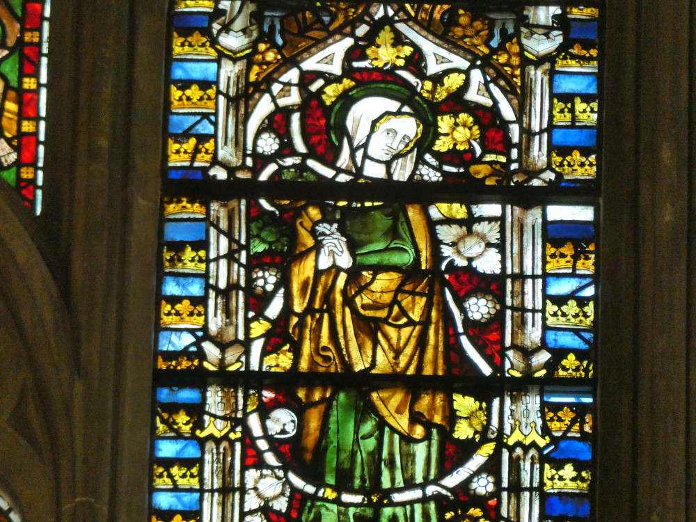 A close-up of one of the figures from the Golden Window. I think this is Mary in her older years. She's wearing a green and gold dress, a green hat and is surrounded by red and gold leaves and fruit.