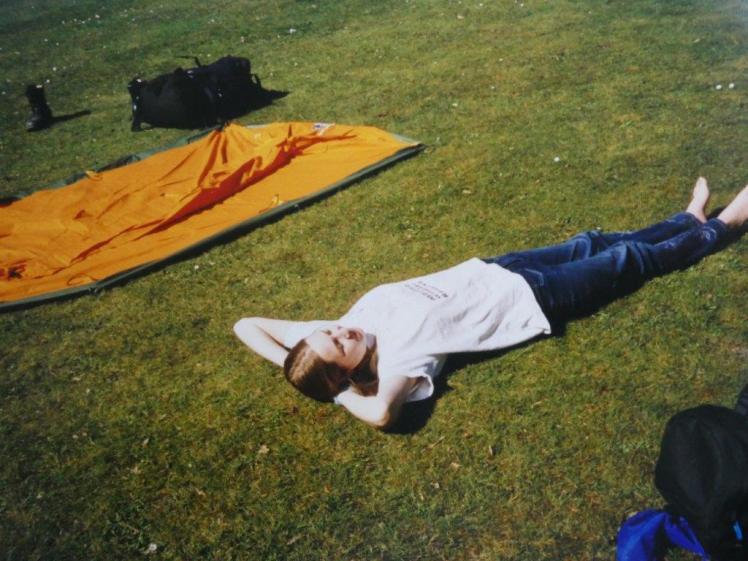 Catherine lying on the grass enjoying the sun. Chris's tent interior is pegged out on the grass next
