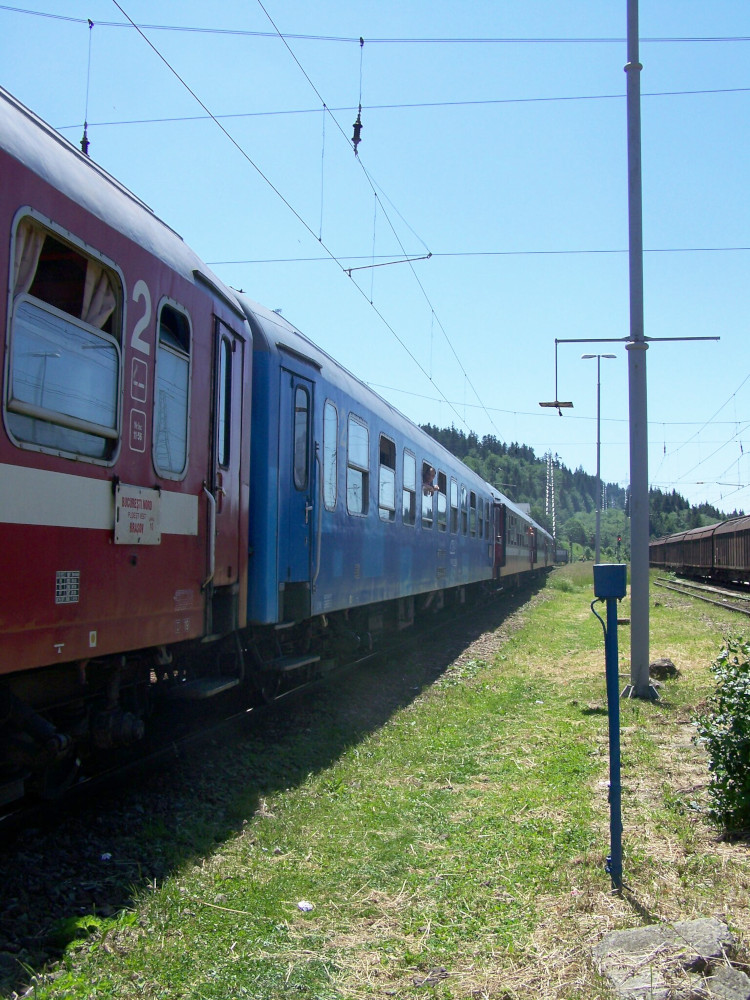 A train with blue and red carriages, stopped outside the station. There is nothing else visible but blue sky and grass. In hindsight, it's very obvious this was not the Transylvanian capital city.