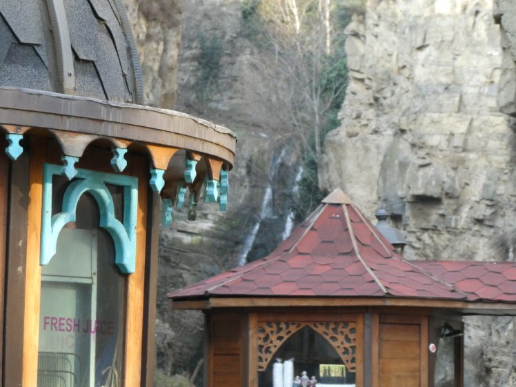 A glimpse of the waterfall, behind a couple of juice kiosks, taken with my good zoom, which is why the kiosks look really close but the waterfall is a bit blurry.