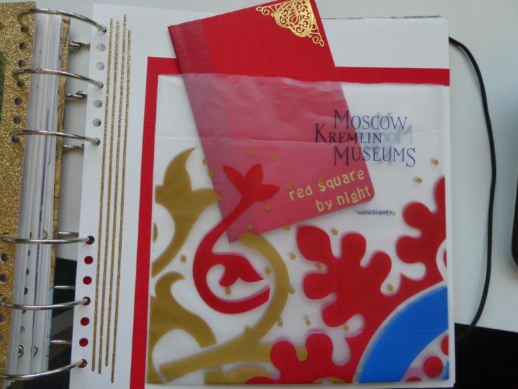 Handmade perfect bound minibook poking out of a plastic bag stuck down on a page.