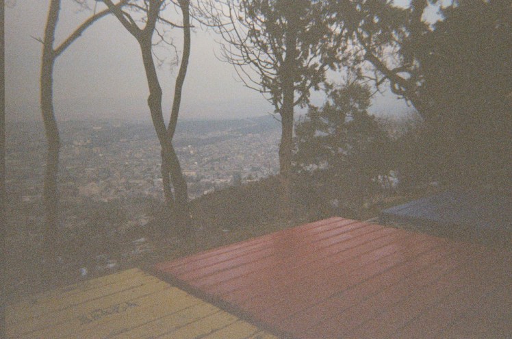 Three oversized colourful benches or wooden "beds" at the edge of Mtatsminda, looking outt at Tbilisi. Again, it's too dark for the film so it's grey, dark and grainy.