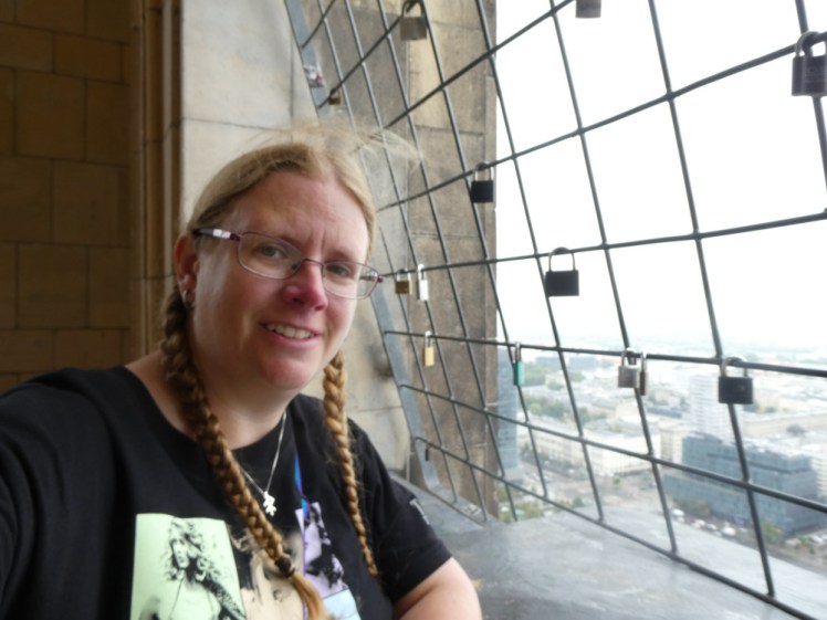 A selfie at the top of the skyscraper, next to one of the meshed-off windows. Now I'm just wearing a t-shirt and I'm freezing (it's my Eras tour t-shirt!).