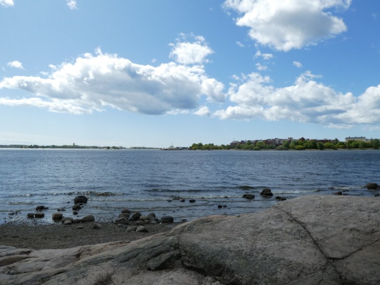 The rocky shore of Korkeasaari, with tree-covered islands on the horizon and geese nesting on the rocks.