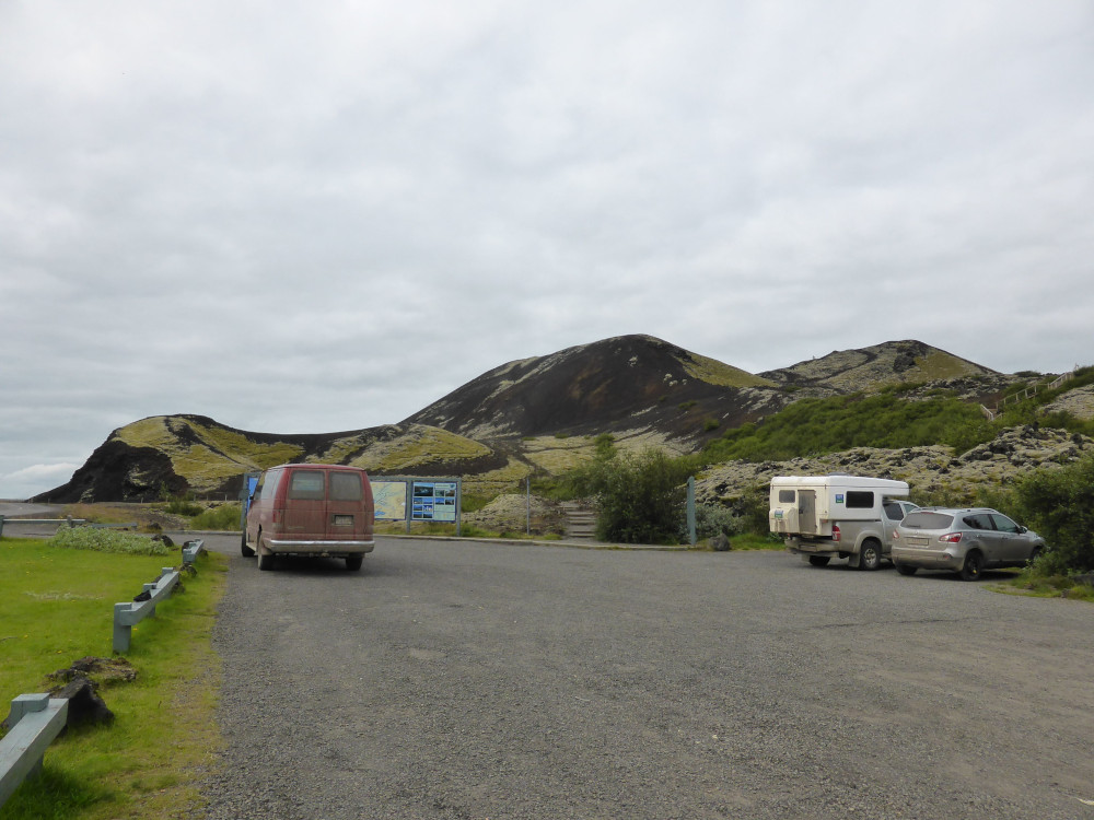 Three small volcano humps as seen from the car park, all reddish-brown and covered in light green moss.