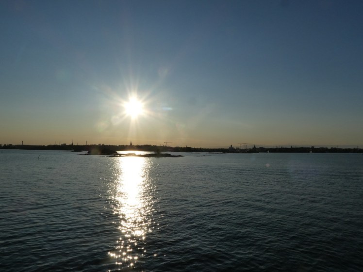 Sunset over Helsinki. Actually, the sun has a good couple of hours more before it sets but it's low enough to reflect on the water, silhouette the city and turn the sky over the horizon pale orange.