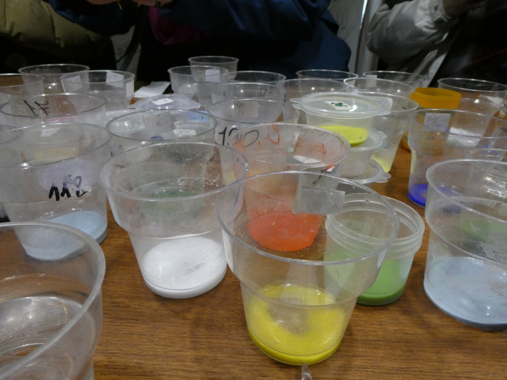 Plastic pots with a little bright-coloured glass powder in water in the bottom.