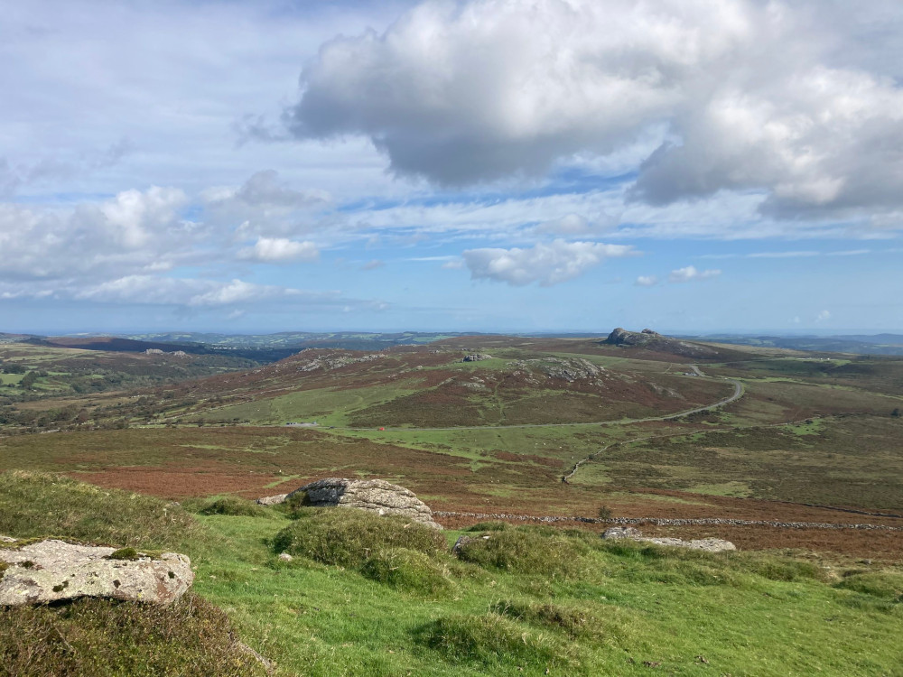 The view north-east from Rippon Tor, looking across quite green moorland to Haytor and Saddle Tor. The sky is blue but there's a bit of threatening cloud starting to loom.