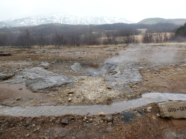 My second-favourite hot spring, Litli-Geysir, a hole in the ground filled with violently bubbling hot water which issues plenty of steam. Behind it, snow-streaked mountains are half-hidden in the cloud.