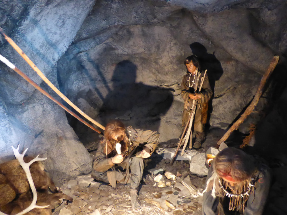 Dummies in fur outfits with bone jewellery huddle around a "campfire" inside the caves.