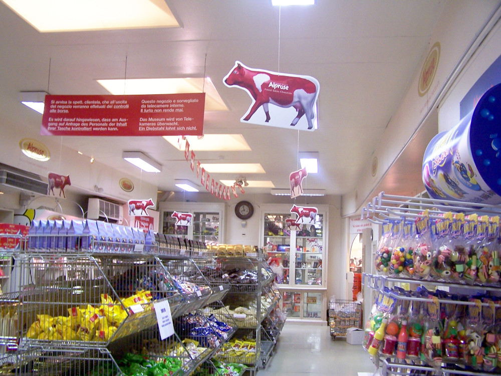Inside the Alprose factory shop - metal baskets loaded with chocolate in wrappers of all colours and red cow logos hanging from the ceiling.
