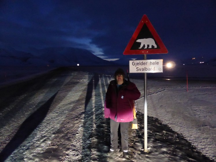 Me posing awkwardly next to a "beware of polar bears" sign, holding the rifle. I'm not entirely happy to be holding a heavy real gun. It's only for the photos - we could never actually carry or use the gun for protection because we're tourists without the right training and qualification.