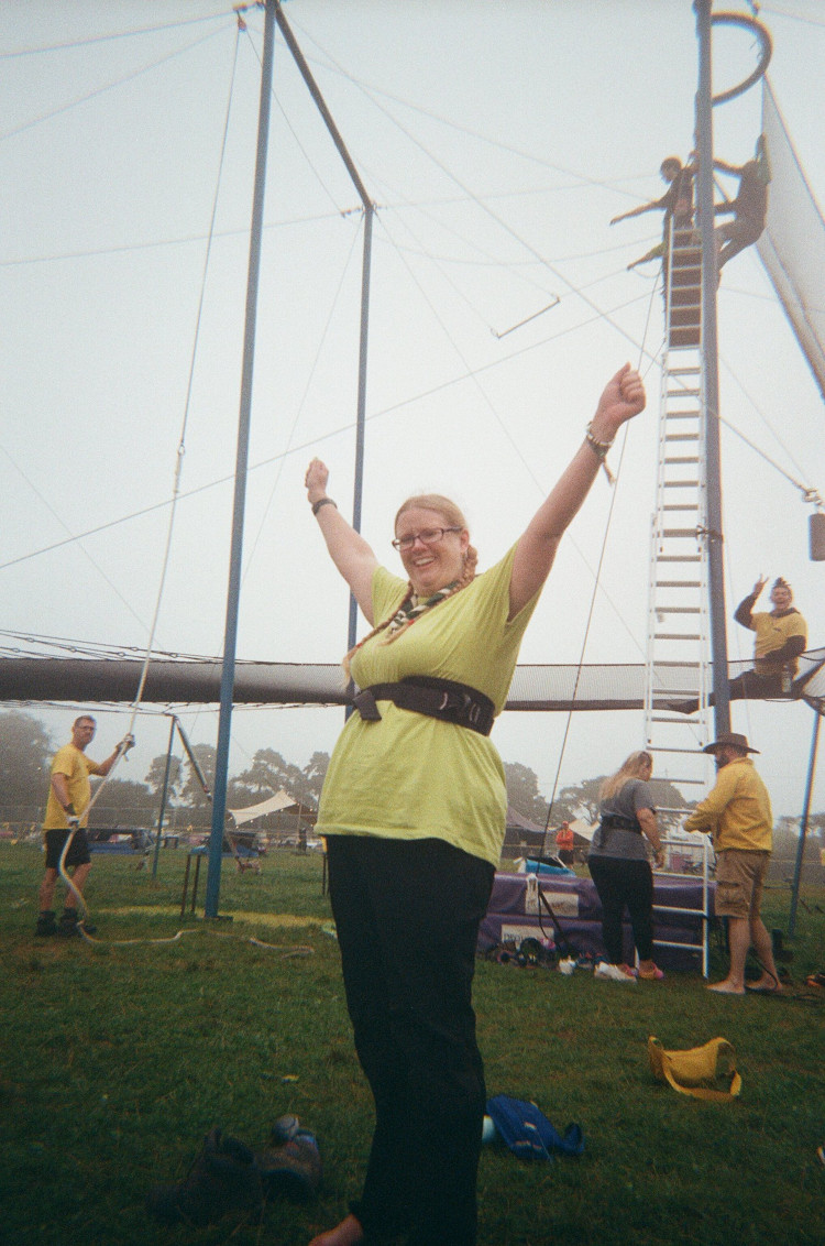 Me after my trapeze jump, arms up in triumph, wearing a harness-belt very high up. Much more comfortable than an actual harness.