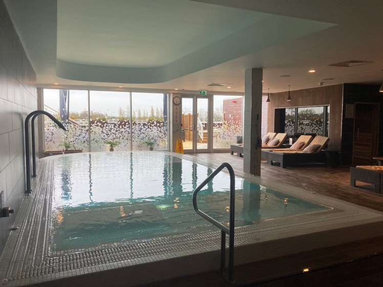 The hydro pool at the spa, a rectangular pool with a rounded end, reclined beds, bubble benches etc. To the right, there's the sauna and the relax room with heated stone beds and you can see outside on the deck through the full-height windows.