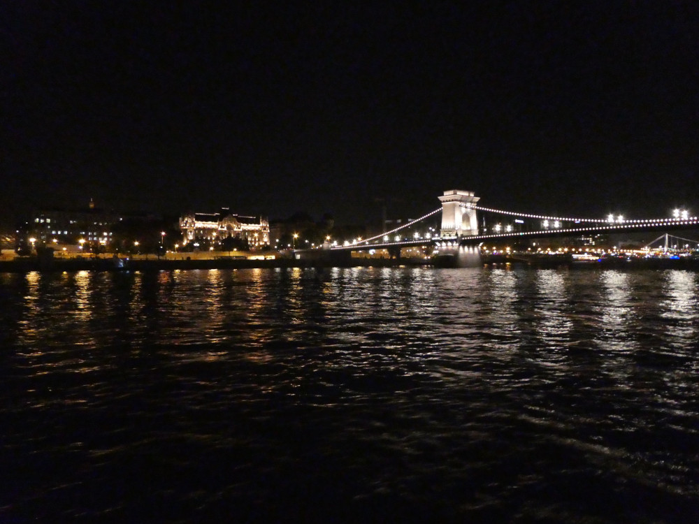 Sailing down the river with the famous Chain Bridge illuminated in white coming up ahead.