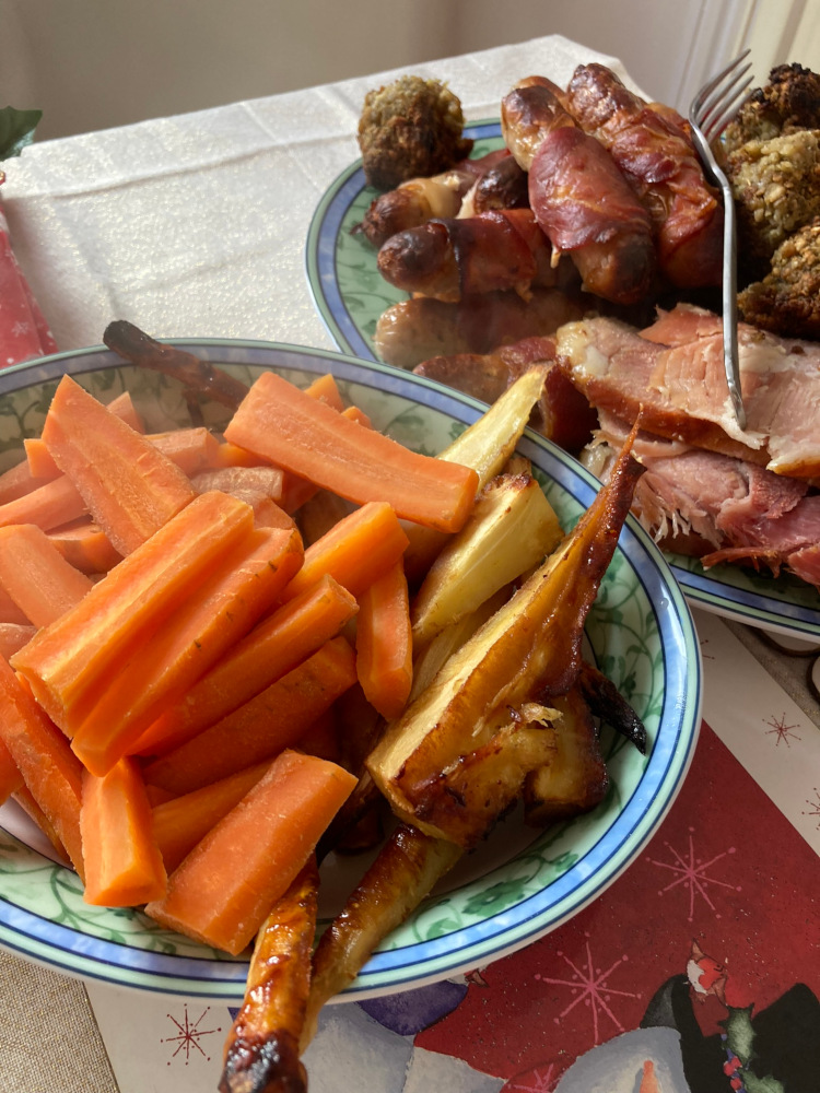A dish of roasted carrots and parsnips (I grew the parsnips). Behind it is a plate of stuffing balls, turkey, gammon and pigs in blankets.