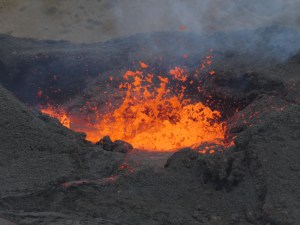 An extreme close-up of orange lava splashing around in a black volcanic crater. It's actually taken from around 400m away with my good zoom lens.