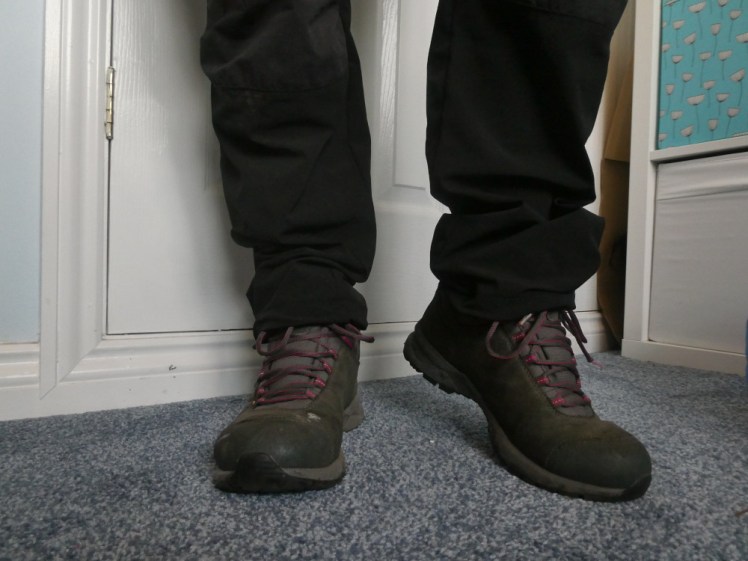 My legs and feet, now clad in a pair of grey boots, reasonably well worn. The hooks for the laces are pink and the grey laces have a pink thread through them. I did not clean this boots before taking the photos.
