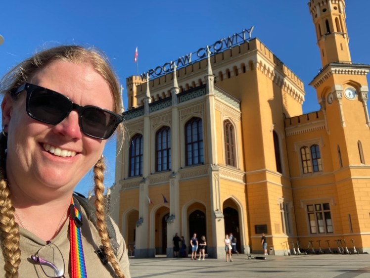 Selfie outside Wrocław station, which is a yellow castle-like building.