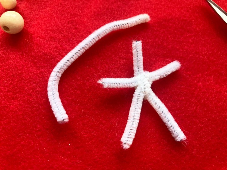 The pipecleaner cut into pieces and twisted together into the shape of a stick person.