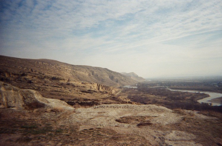 The view east from Uplistsikhe, with mountains stretching away and a river snaking along the bottom.