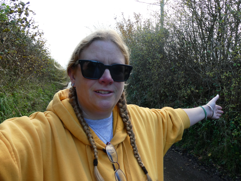 A selfie in a yellow hoodie and sunglasses down a shaded winter country lane.