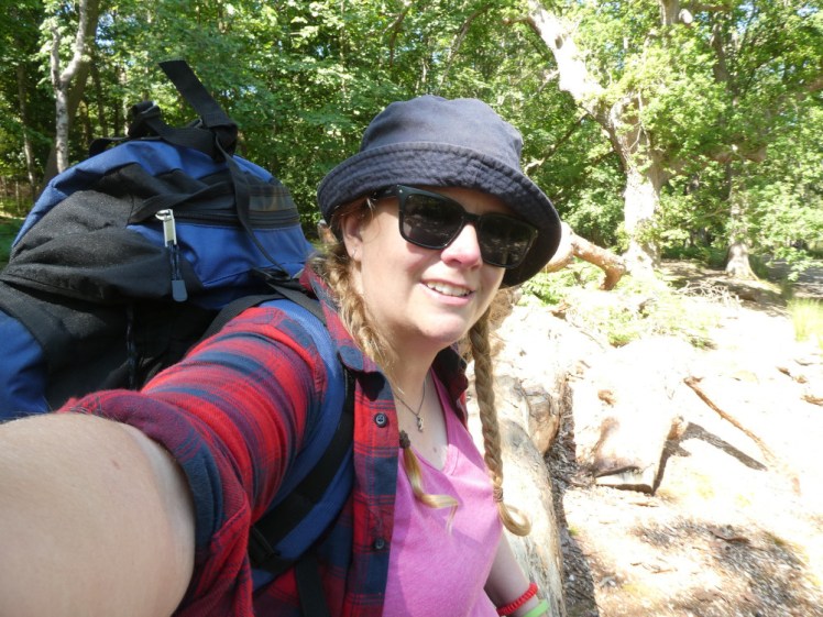 Me on Brownsea last year, wearing a pink vest, a red and blue checked shirt, a navy bucket hat and carrying a blue 65l backpack.