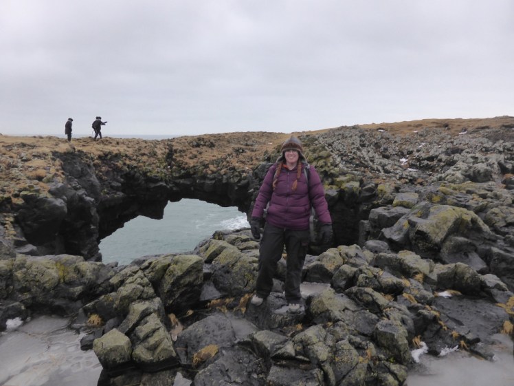 Me standing in front of a natural rock bridge at Arnarstapi on Snæfellsnes. I'm wearing a woolly hat shaped like a Viking helmet, a