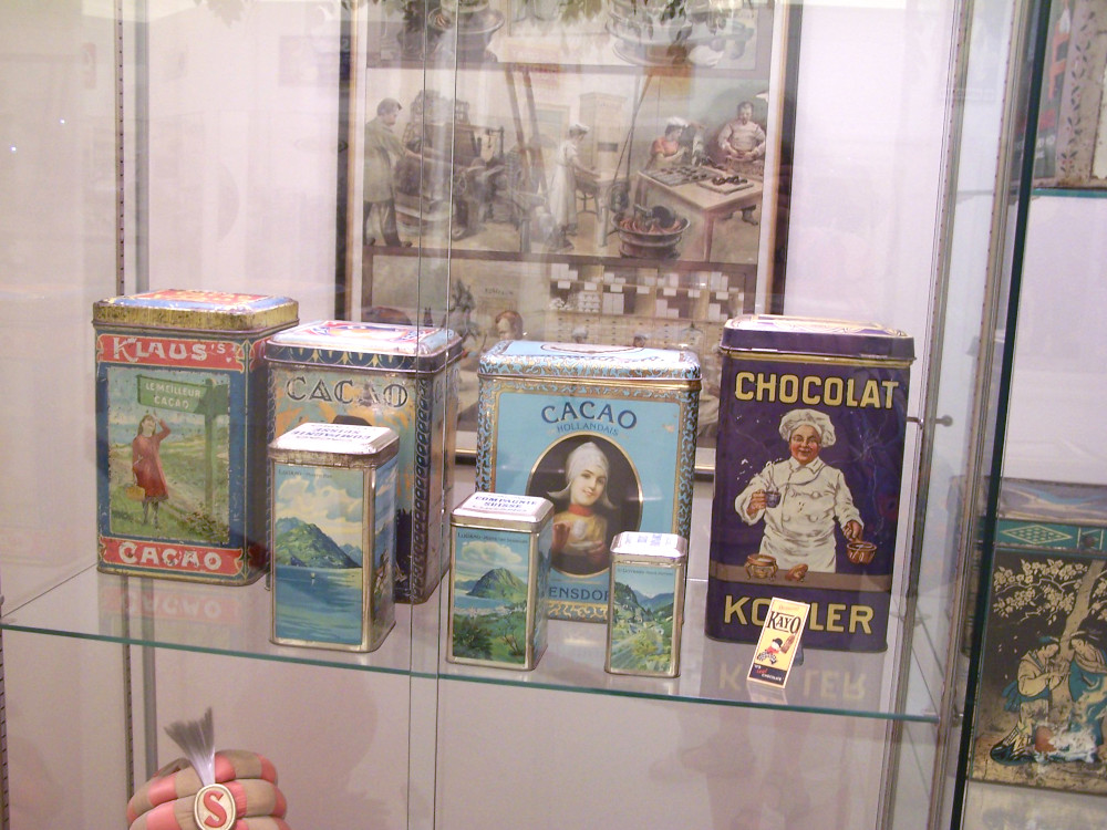 Vintage chocolate tins in a glass cabinet.