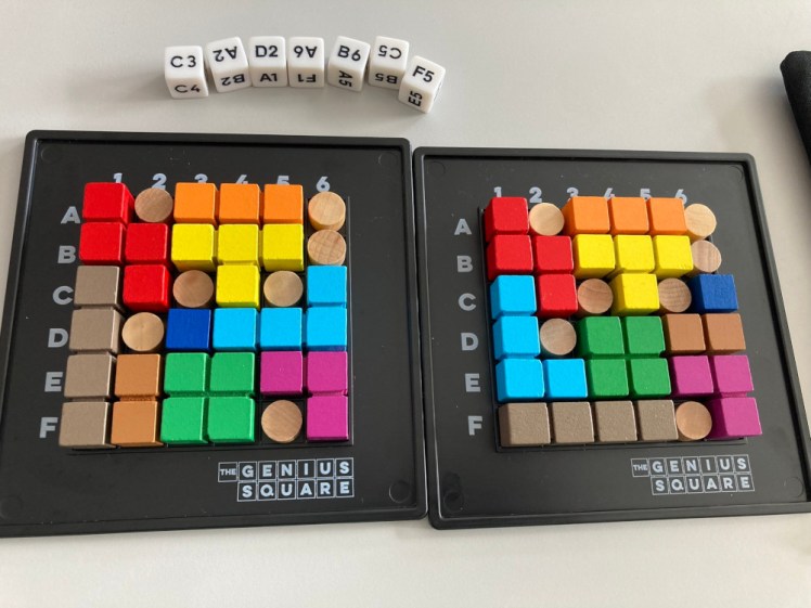 The Genius Square, a game where dice decide which squares wooden blockers go in and then players have to use their Tetris-like pieces to fill the spaces all around. In this example, my opponent & I have managed to do it completely differently (she won, it's fastest to complete it).