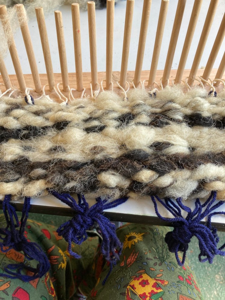 The weaving now slid down the pegs and onto the warps, the navy yarn tied on the bottom of the pegs.