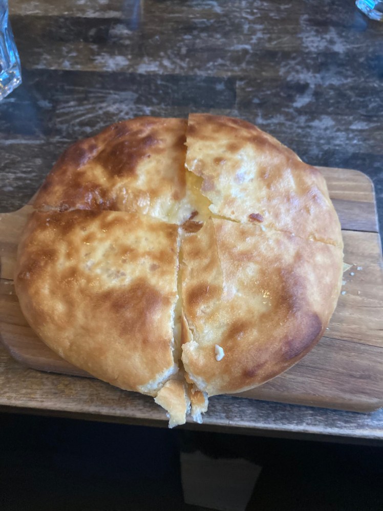 A small round puffy flatbread cut into quarters so you can't quite see that it's absolutely full of cheese.