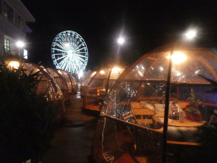 The Alpine bar with the big wheel in the background. The bar is made up of plastic domes filled with wooden benches, rugs, blankets and various cosy Nordic stuff.