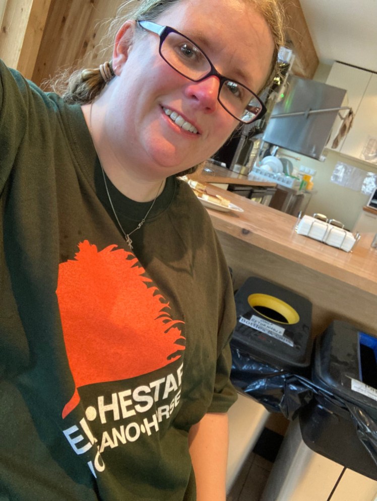 A selfie in the Eldhestar canteen, trying to get as much of my new, dry oversized t-shirt in as possible. It's a khaki green and has a big orange horse's head on it, with the words Eld•Hestar / Volcano Horses underneath.