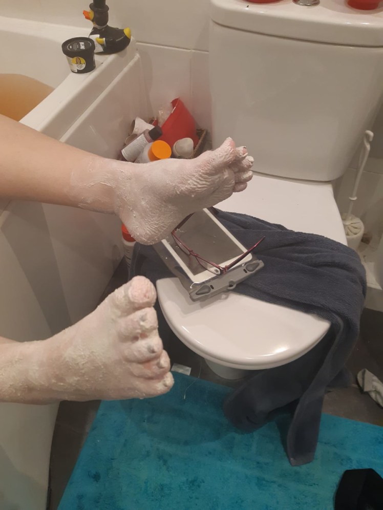 Feet with Volcano clay mask hanging over the bath